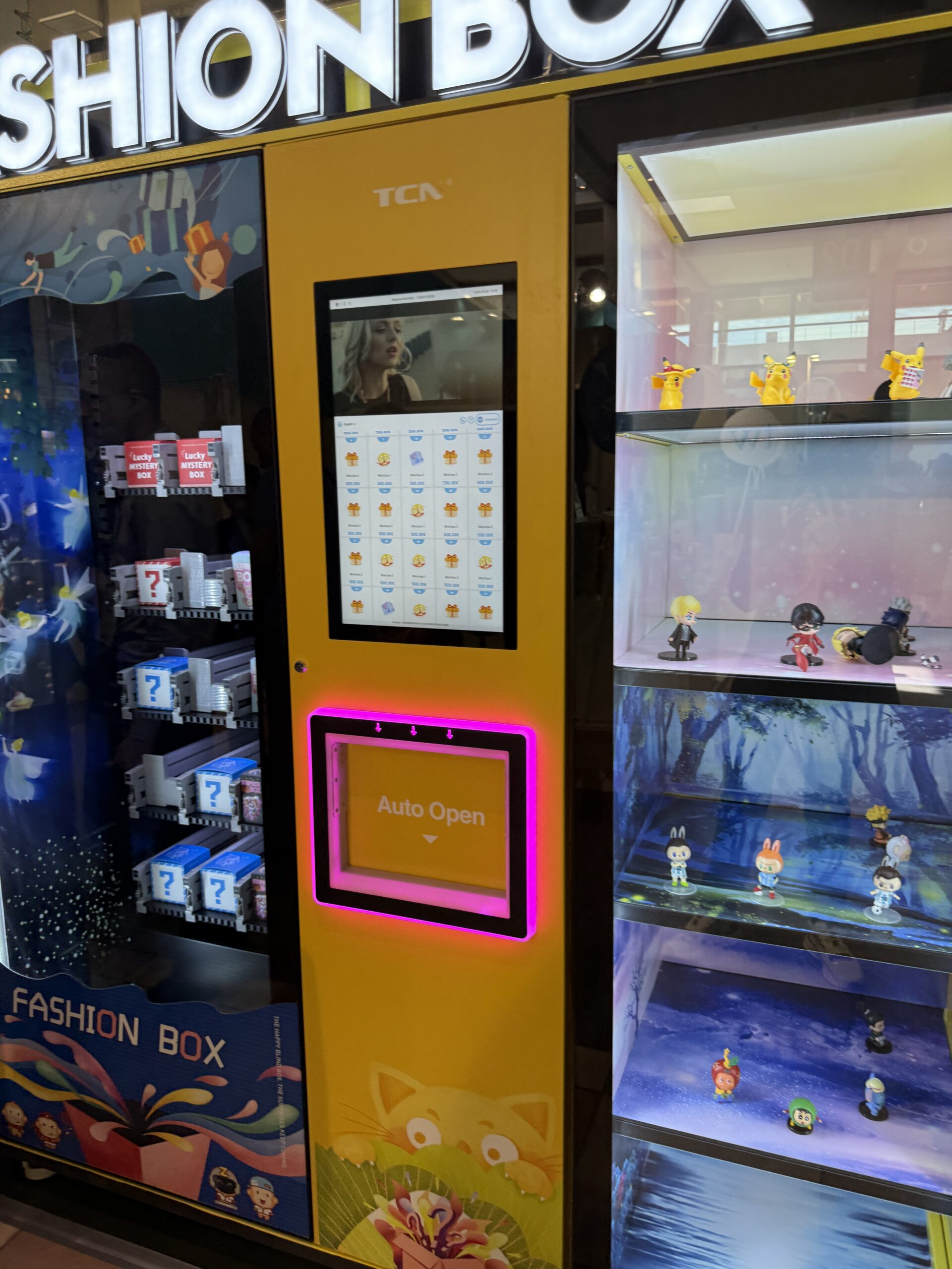 Lit display case with collectible figures beside a trading card vending machine, functioning as brand real estate