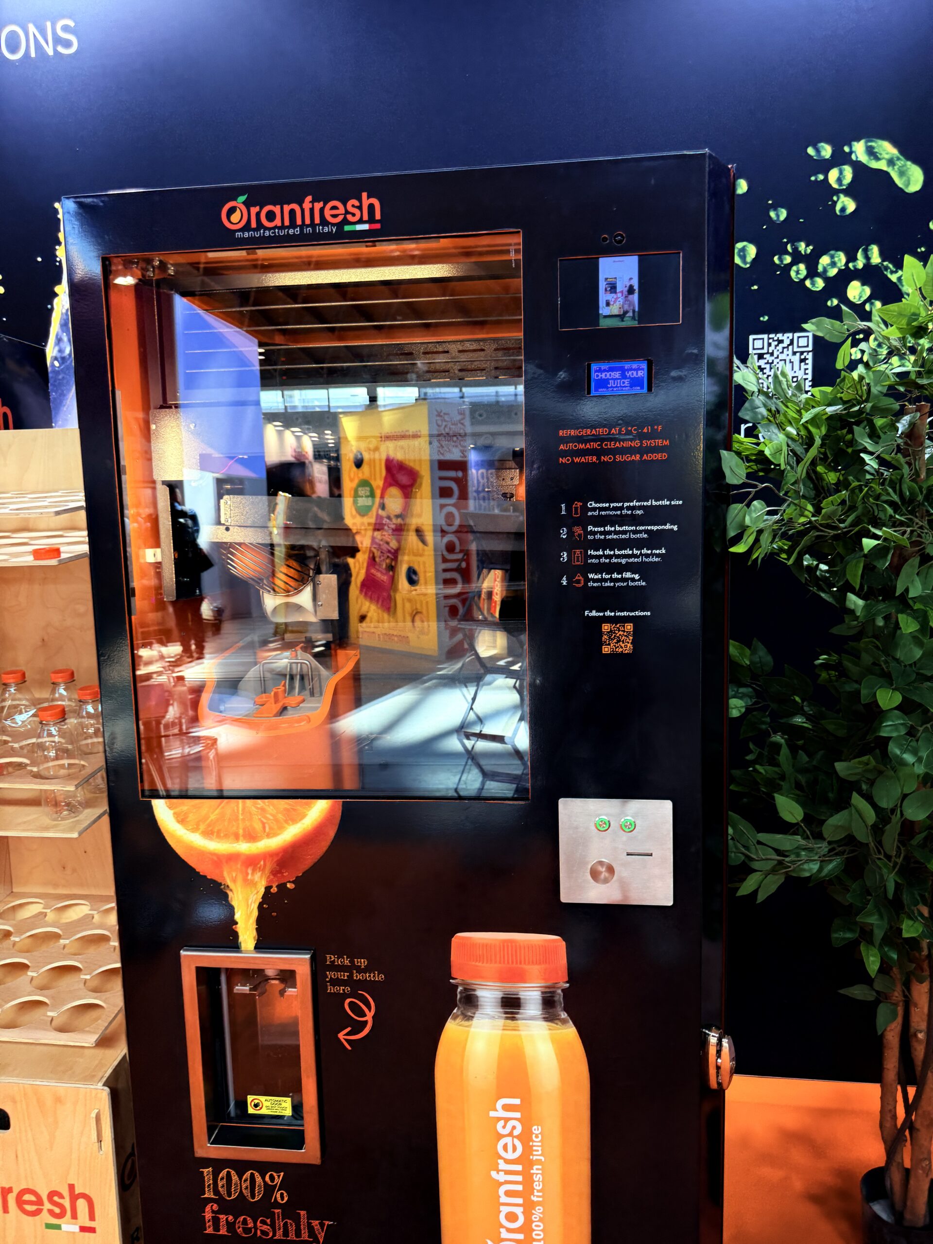 Fresh juice vending machine juicing oranges on demand behind glass