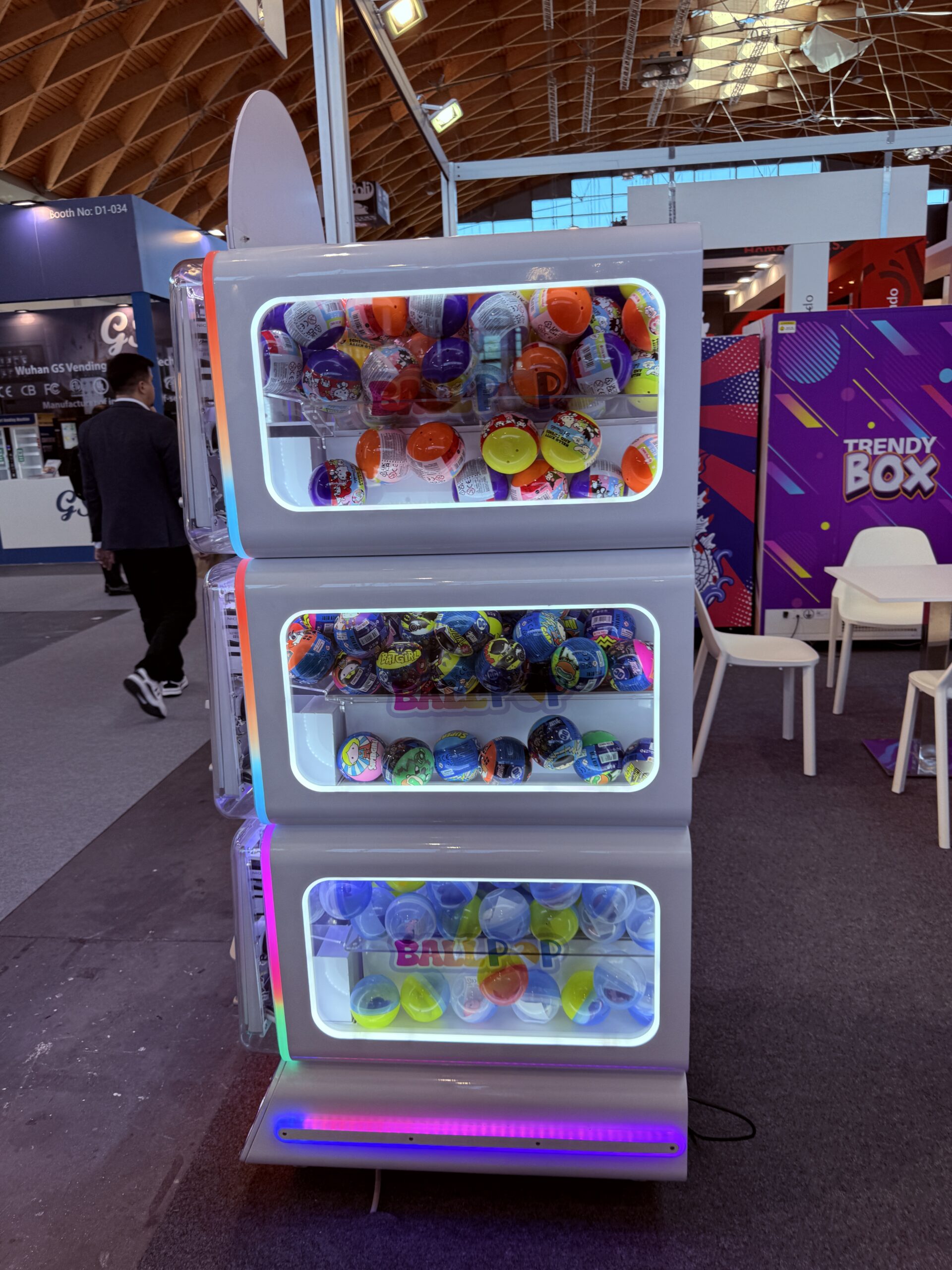 Stacked mystery ball vending machines with brightly lit display windows full of capsules